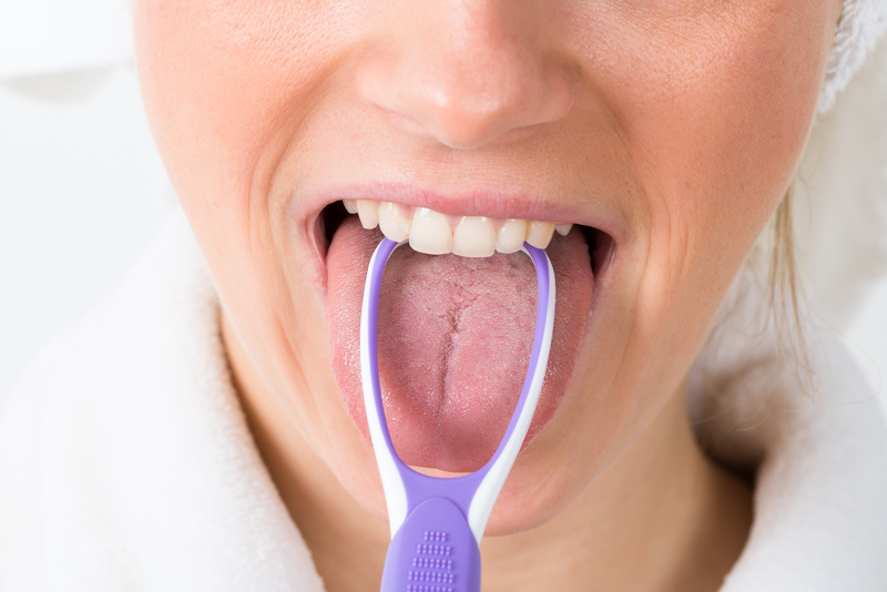 Woman using a tongue scraper